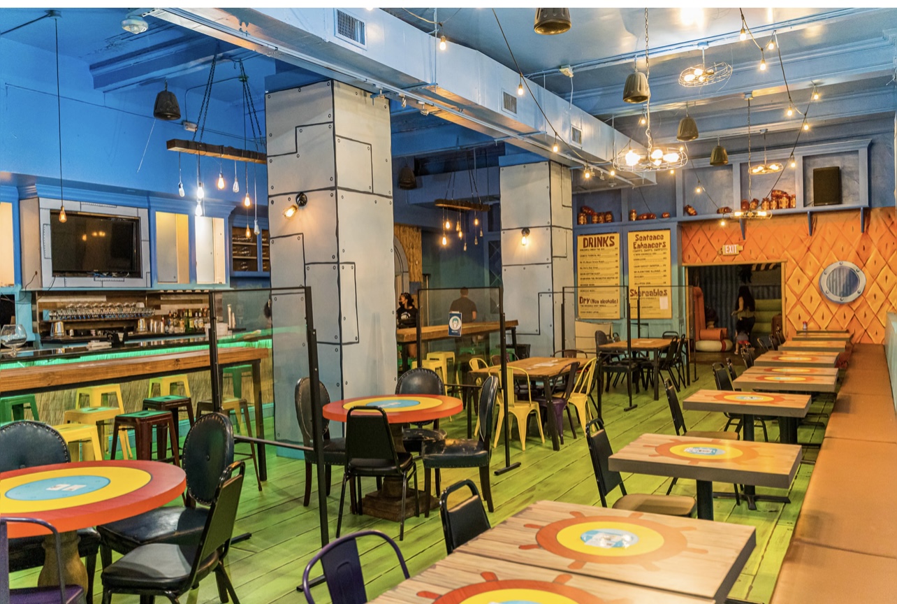 Underwater themed pop-up bar interior with custom seating and branded signage in Houston